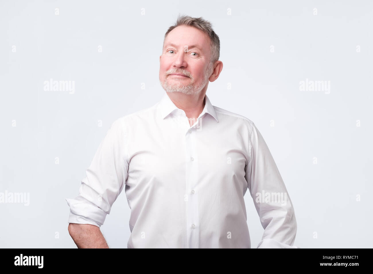 Smiling senior man in white shirt standing and smiling at camera sentiment bon Banque D'Images