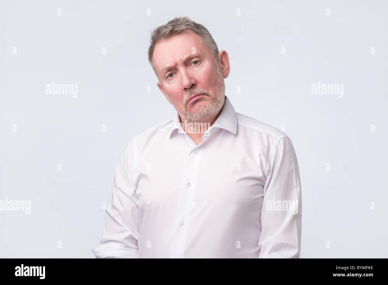 Old man en chemise blanche avec de graves et expression triste. Banque D'Images