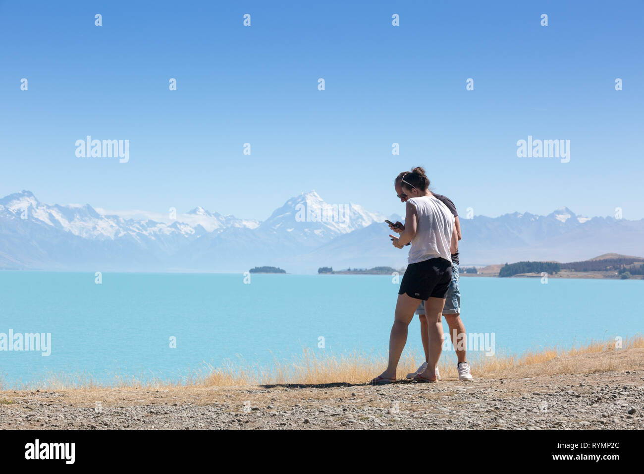 Deux jeunes gens profitant de la vue, le Lac Pukaki, Nouvelle-Zélande Banque D'Images