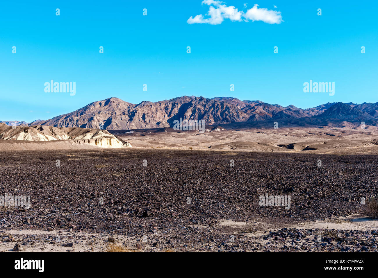 Champs rocailleux arides avec des montagnes désolées sous ciel bleu. Banque D'Images
