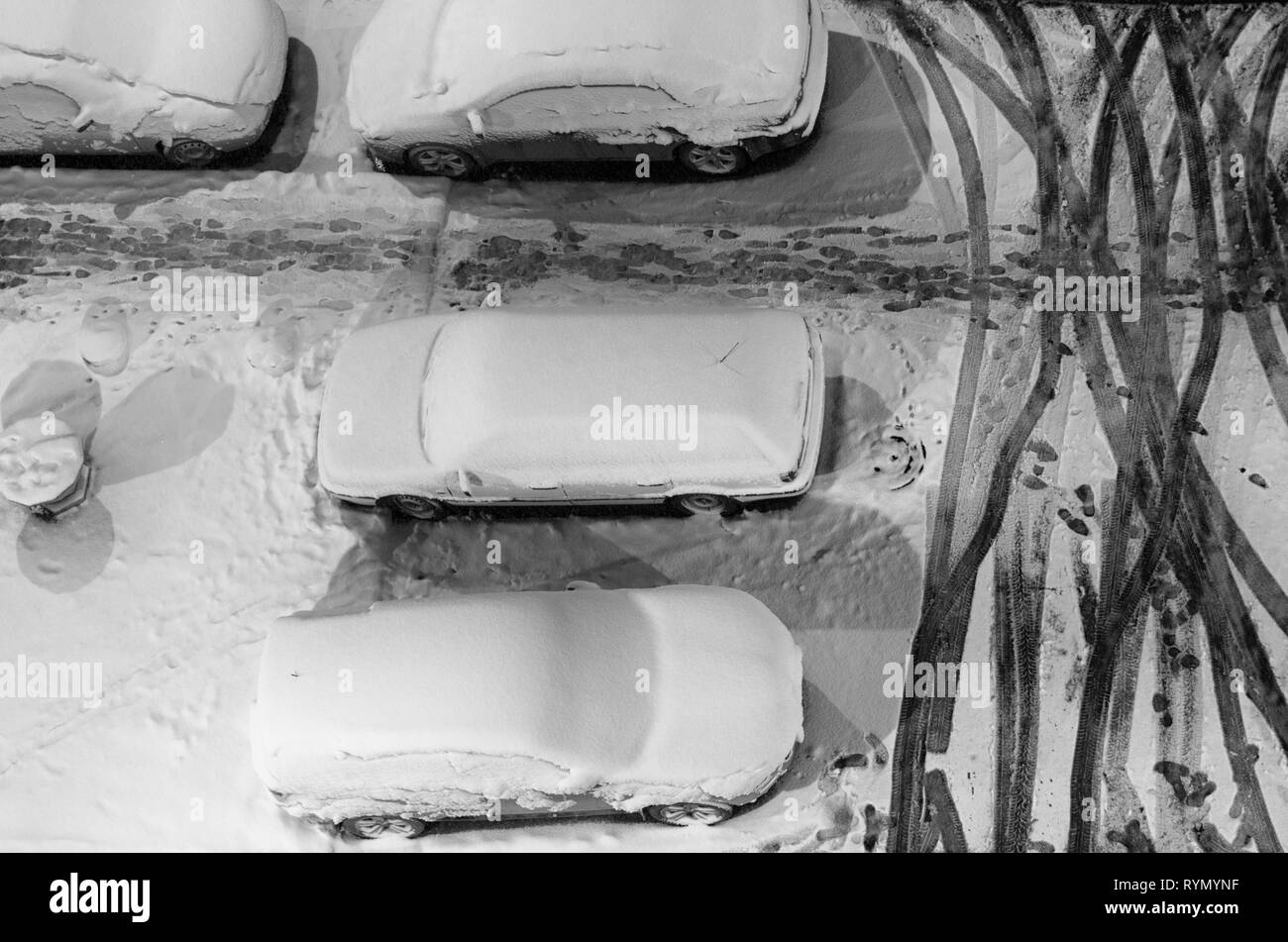 Les voitures en stationnement et des traces de pas dans la neige en noir et blanc vue de dessus de style Banque D'Images