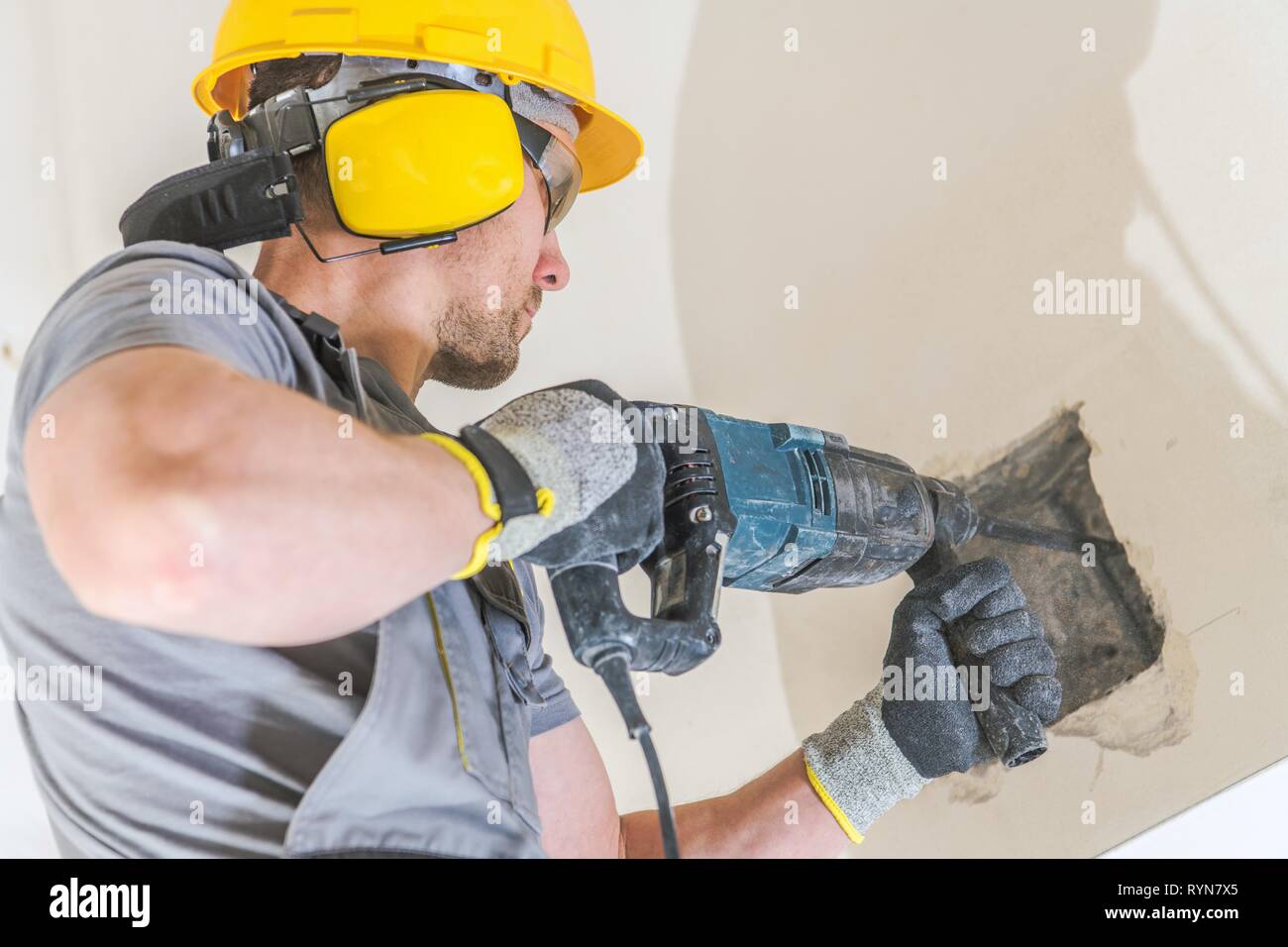 Travailleur avec marteau-perforateur. Percer des trous dans un mur pour une poutre en bois de l'installation. L'industrie de la construction. Banque D'Images