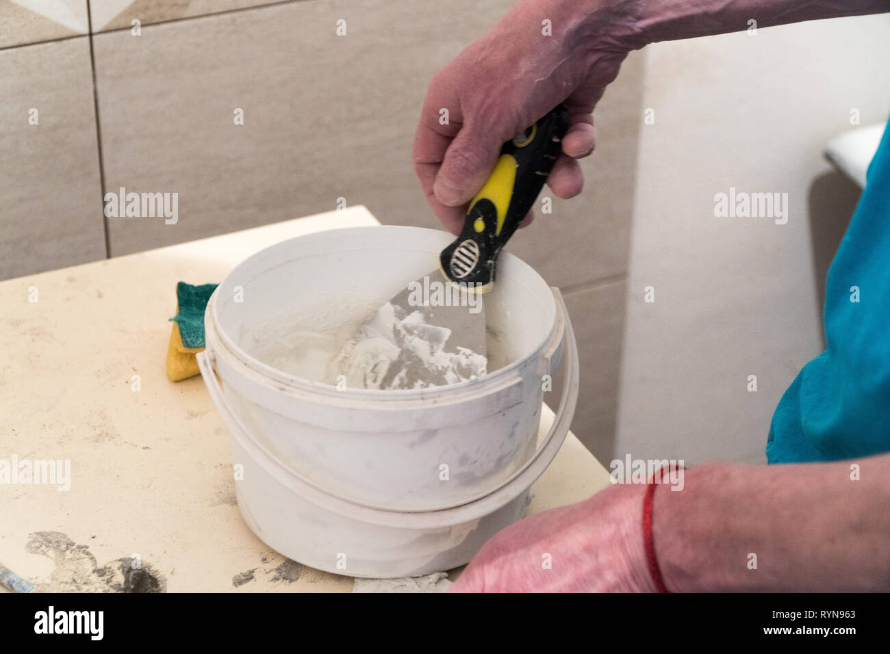 Le travailleur se prépare dans un seau pour les carreaux putty joints. Travaux de finition. La technologie de pose de tuile. Banque D'Images