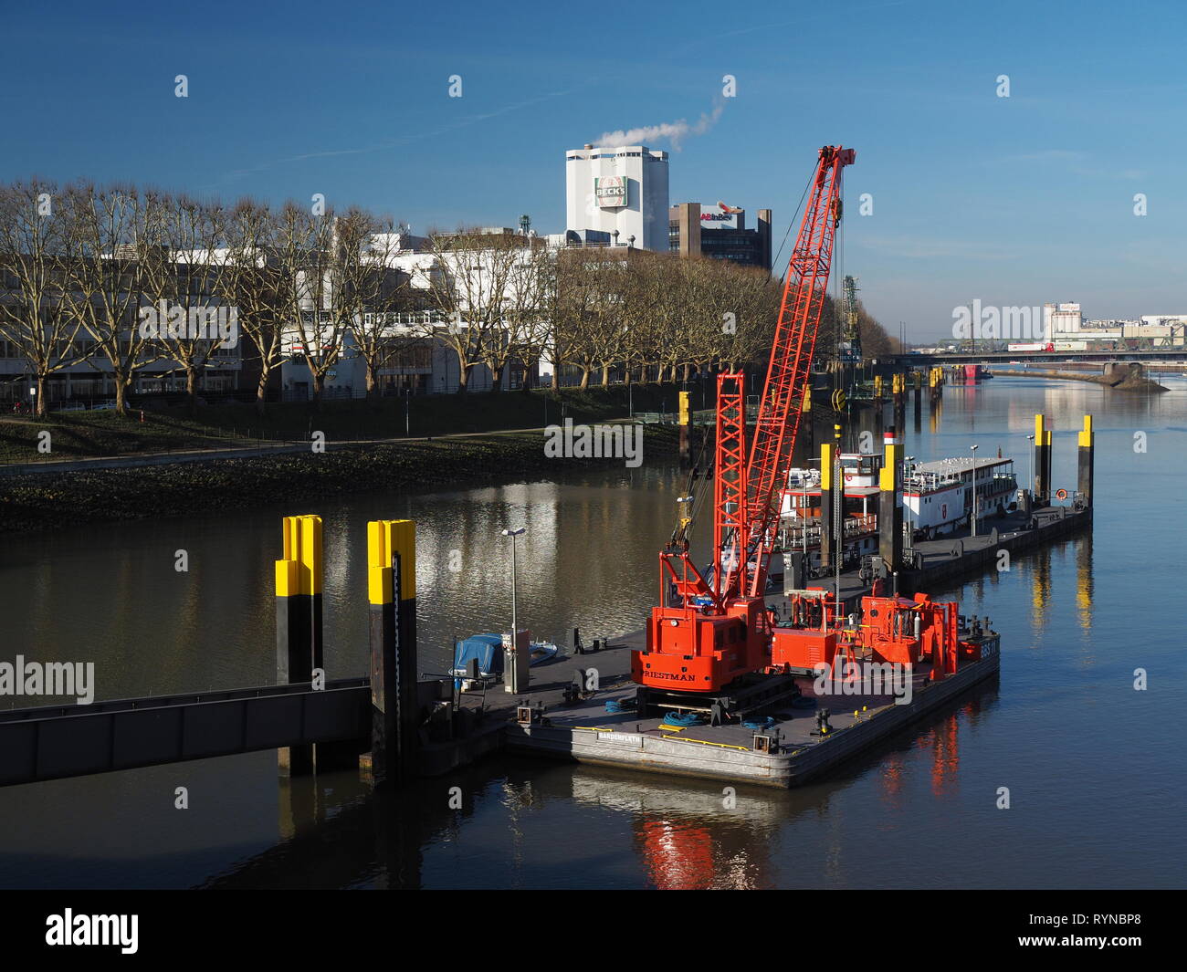 Bremen, Allemagne - 14 février 2019 - Pier avec plusieurs petits navires et grue flottante rouge vif et sur les toits de la ville avec brasserie Beck à l'arrière Banque D'Images