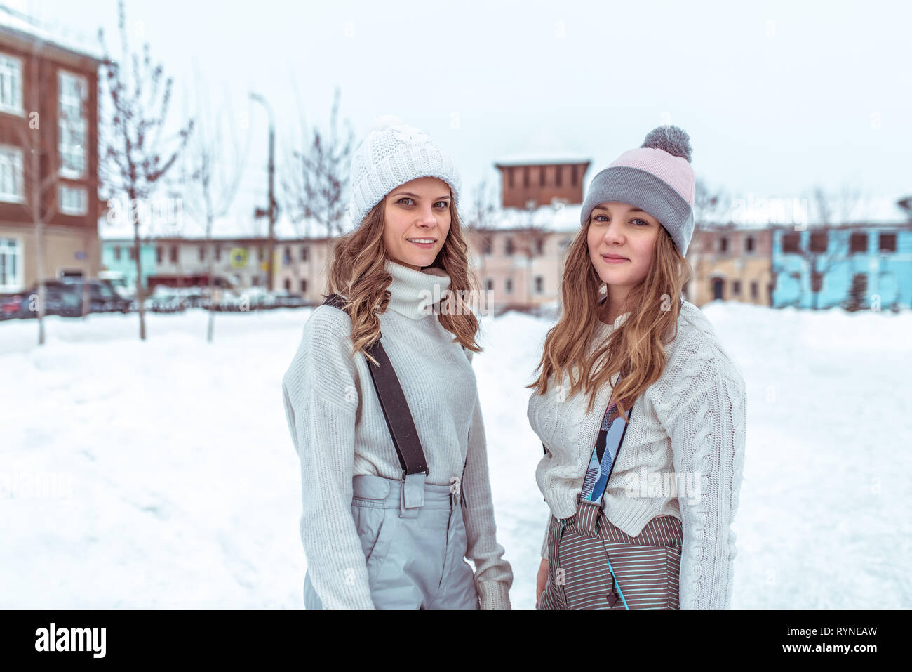 Deux jeunes filles amies en hiver dans la ville, se tenir en salopette dans pulls et accueil chaleureux des chapeaux, sur une patinoire de la ville. Happy smiling, détente à la Banque D'Images