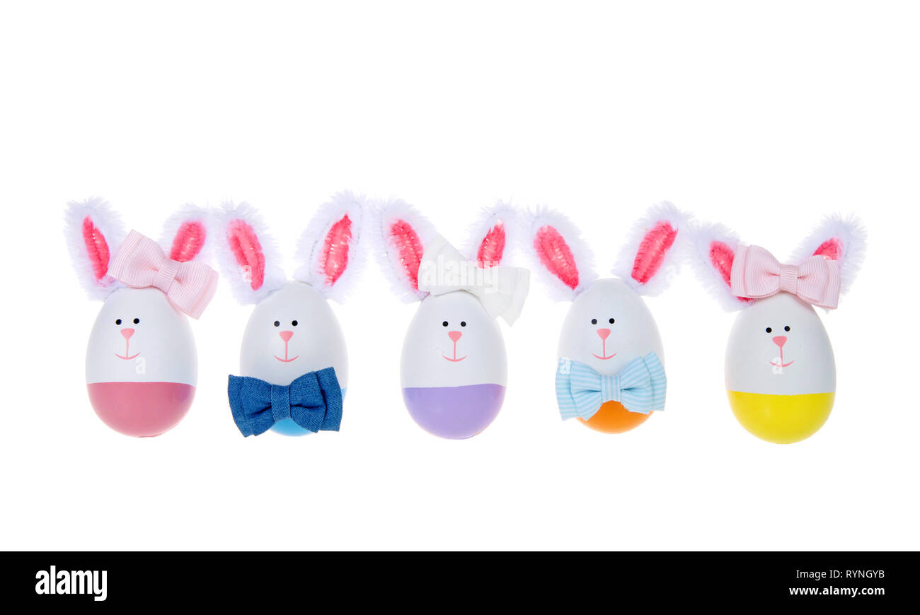 Rangée d'oeufs de Pâques conçu dans lapins, garçons et filles, portant des arcs et de l'oreille sur la queue isolé sur fond blanc. Banque D'Images