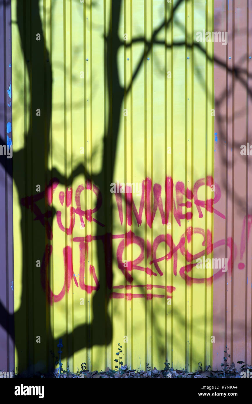 L'ombre des branches et le tronc d'un arbre sur le checker plate d'un immeuble industriel à côté du slogan : Forever Ultras. Banque D'Images