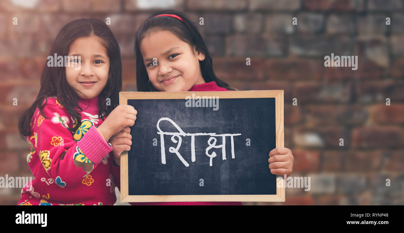 Adorable petit 6-8 ans et 8-10 ans filles indiennes smiling holding, l'éducation (Shiksha) tableau. Banque D'Images