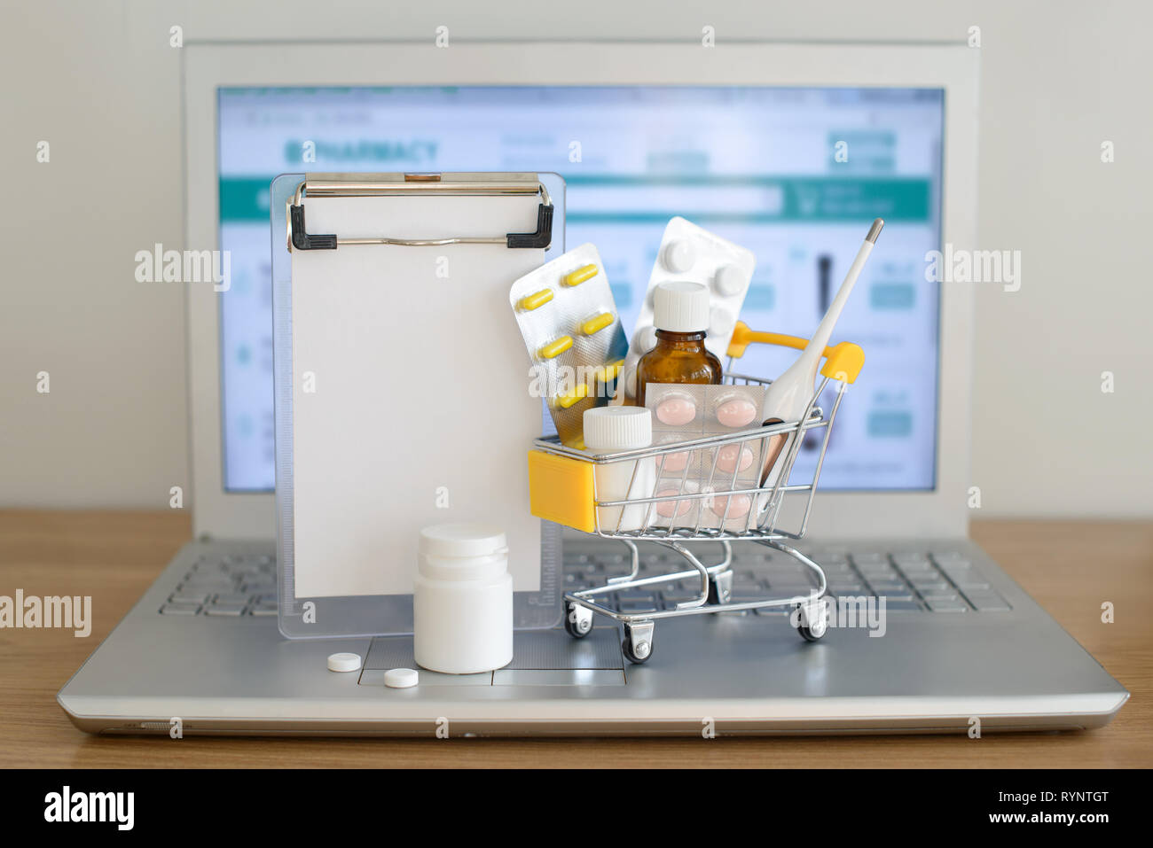 Panier jouet avec des médicaments et du papier remarque devant un écran d'ordinateur portable avec pharmacie site web sur elle. Comprimés, blisters, flacons médical, therm Banque D'Images