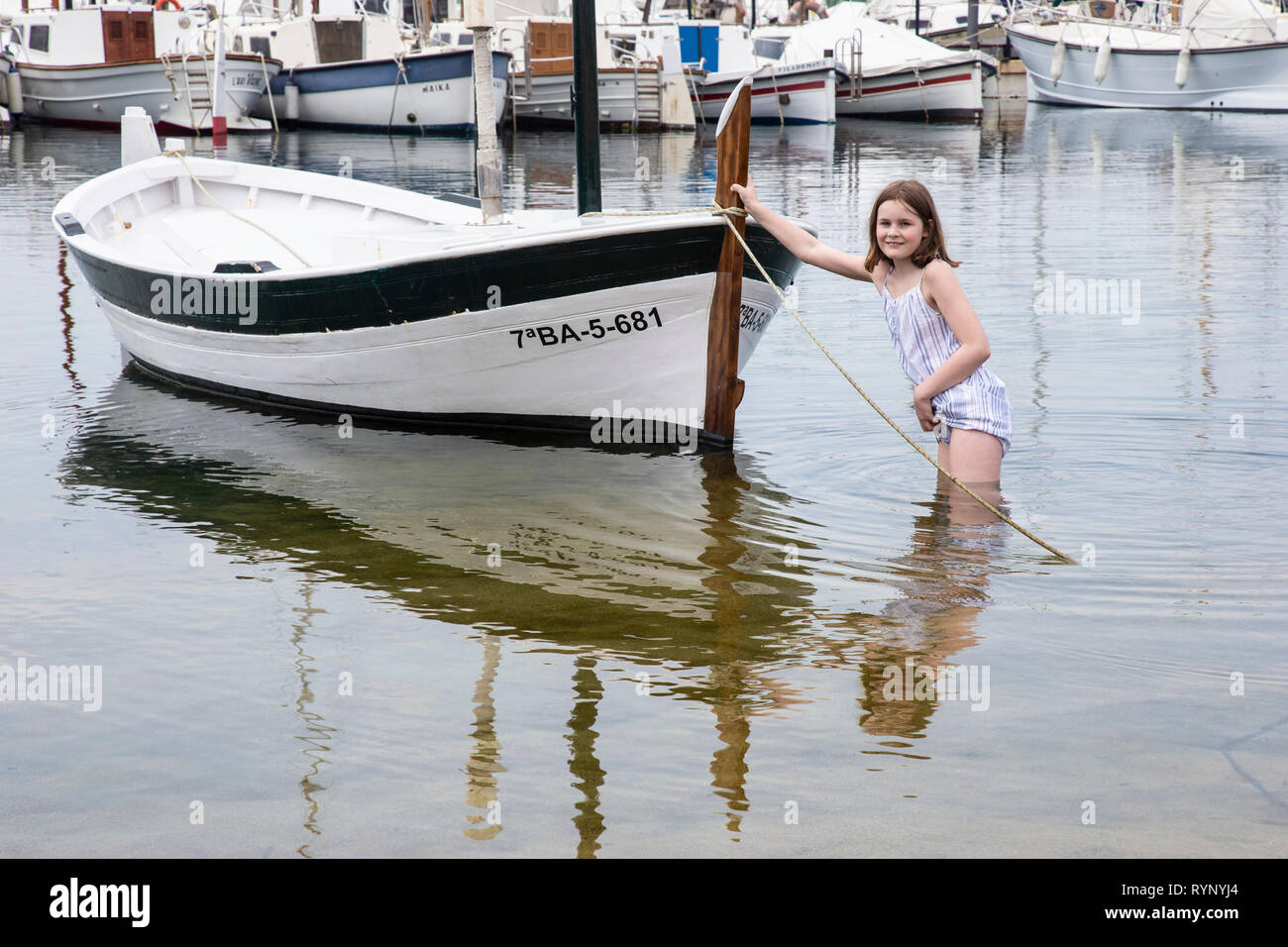 Jeune fille pousser un bateau à rames en eaux peu profondes dans la mer à Palamos en Espagne Banque D'Images