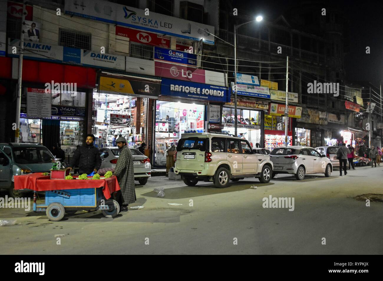 Un vendeur de fruits vu l'attente pour les clients au cours du temps le soir à Srinagar, au Cachemire. Le Cachemire est la région géographique la plus au nord du sous-continent indien. Il est en ce moment un territoire contesté, administré par trois pays : l'Inde, le Pakistan et la Chine. Banque D'Images