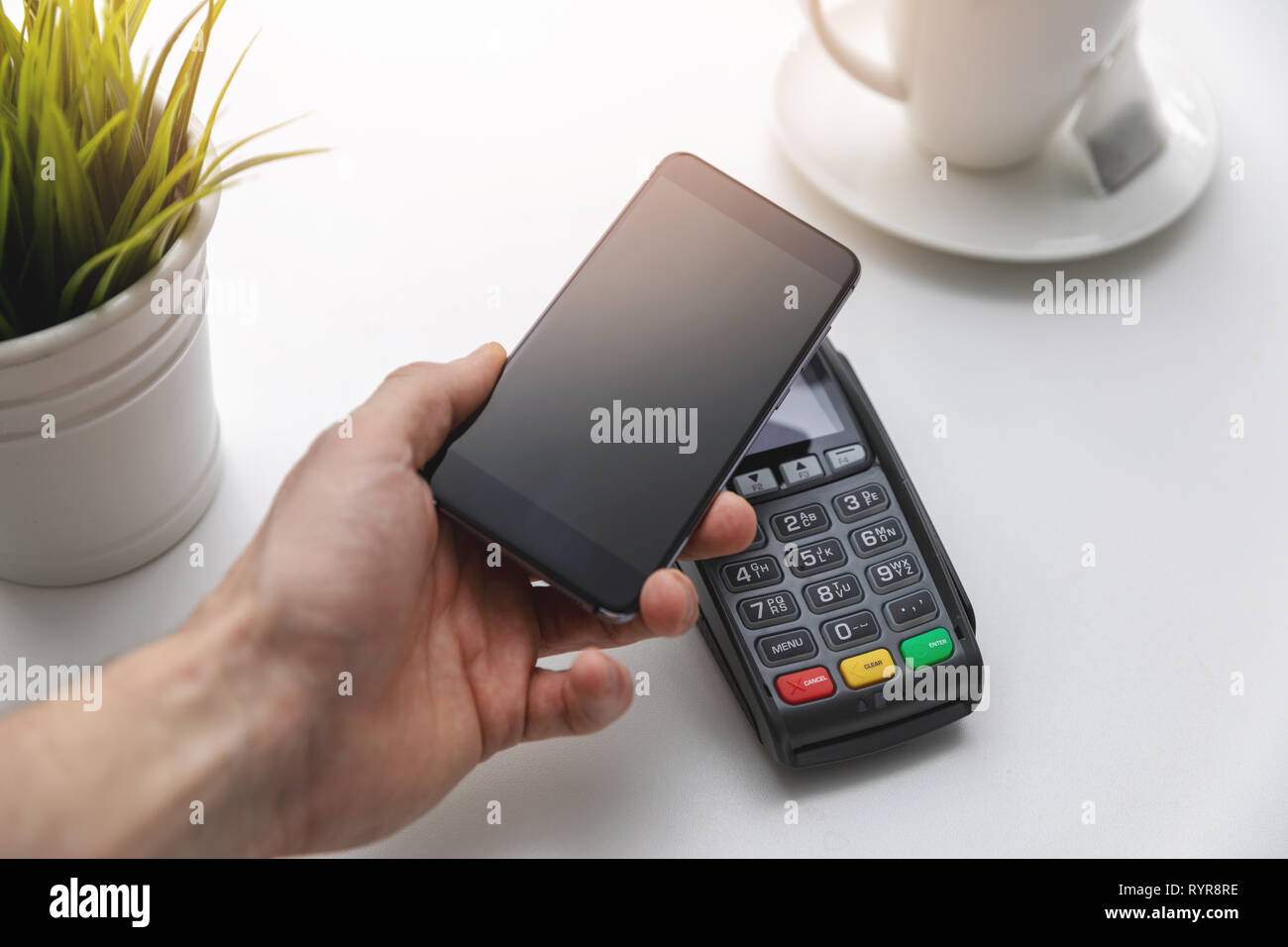 Les paiements sans contact NFC - hand holding phone terminal de paiement ci-dessus Banque D'Images