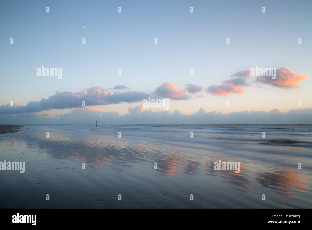 Les nuages reflètent dans les sables à West Wittering dans West Sussex au coucher du soleil Banque D'Images