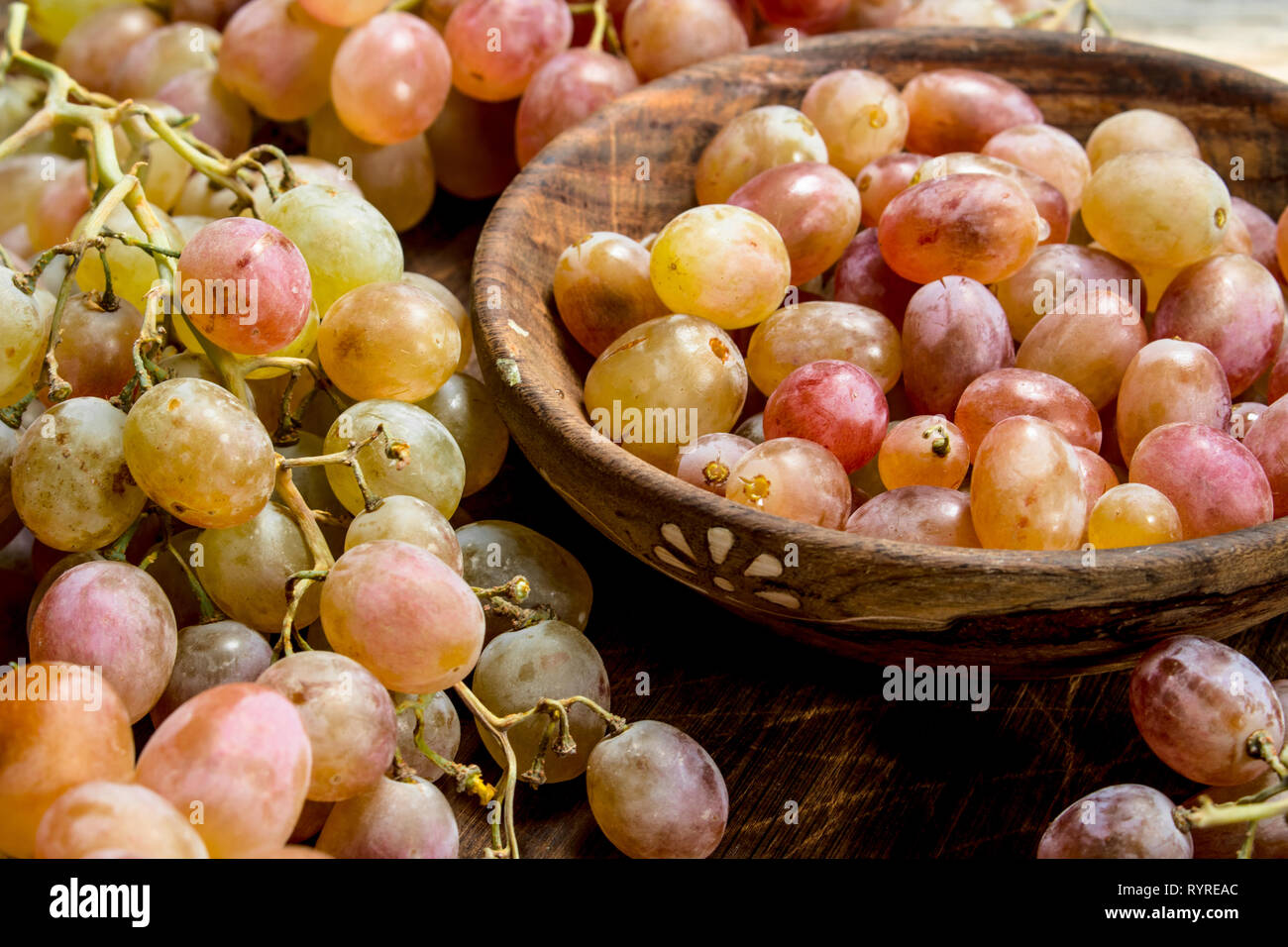 Les raisins dans un bol rose . Sur un fond de bois. Banque D'Images