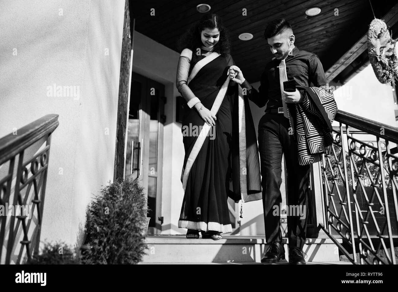 Joli couple indien dans l'amour, à l'usure et élégant costume, saree posés sur une terrasse ensoleillée le jour d'été, la marche en bas et maintenez les mains ensemble. Banque D'Images
