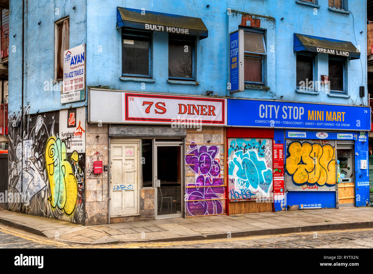 Le coin de Gunthorpe et Wentworth rues de l'East End londonien. Les entreprises fermées de graffiti et tagged artwork. Banque D'Images