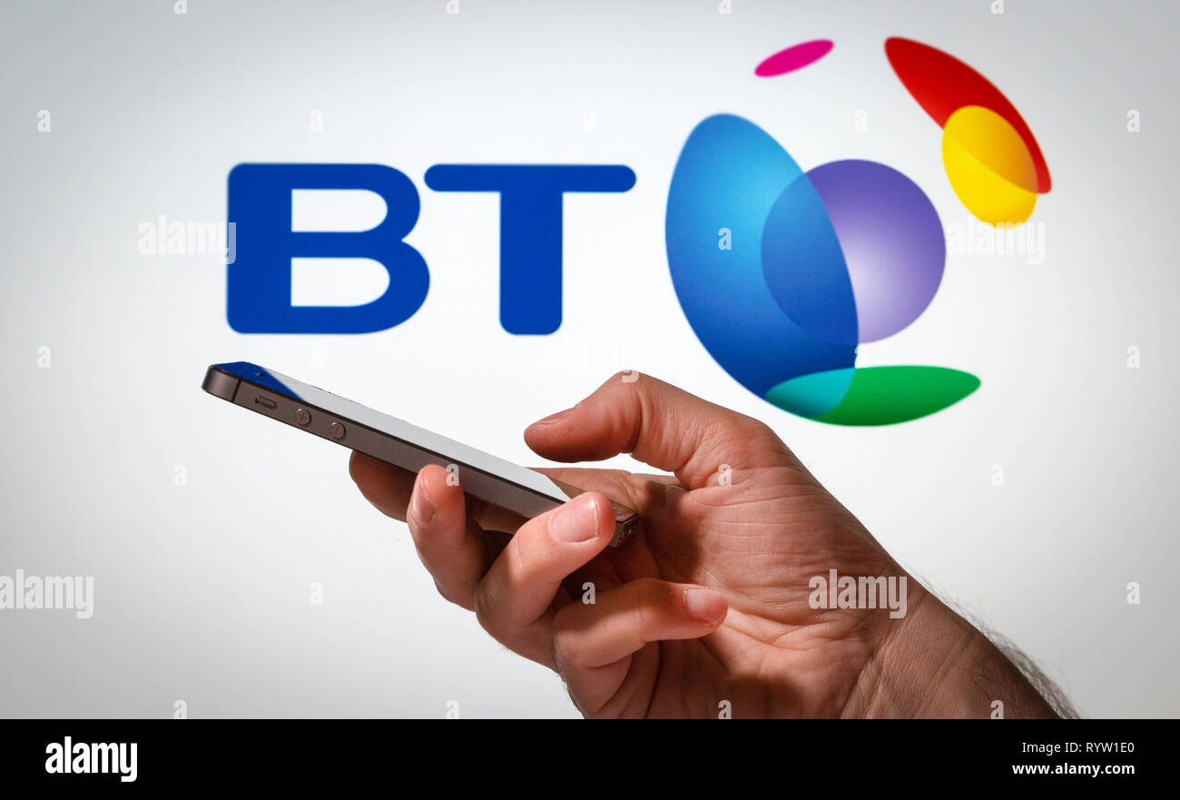 Un homme à l'aide d'un téléphone mobile en face d'un BT sign Banque D'Images