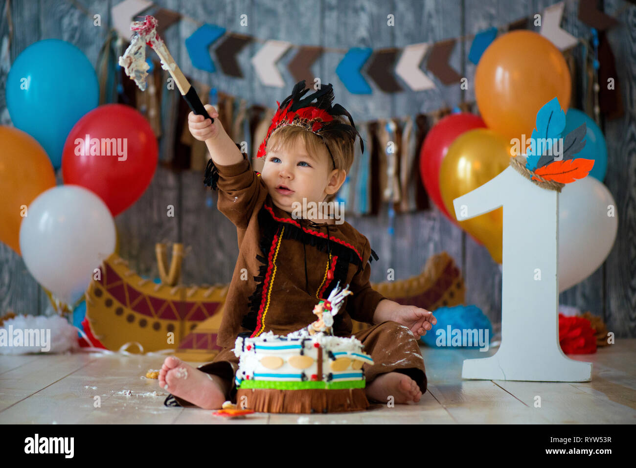 Shoot Photo Smash Le Gateau Pour 1 Annee Dans Le Style De Chef Indien Petit Garcon Avec Un Tomahawk Emotionnelle En Costume D Apache Et Dans La Coiffure De Plumes Photo Stock