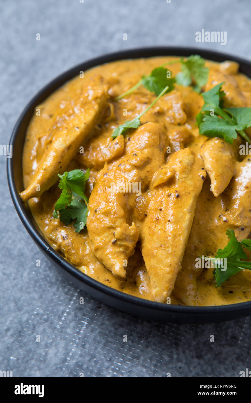 Close up avec vue latérale d'un bol de curry de poulet kurma. Bol de curry Indien d'épaisseur. Bol de poulet korma curry épais avec fond gris. Banque D'Images