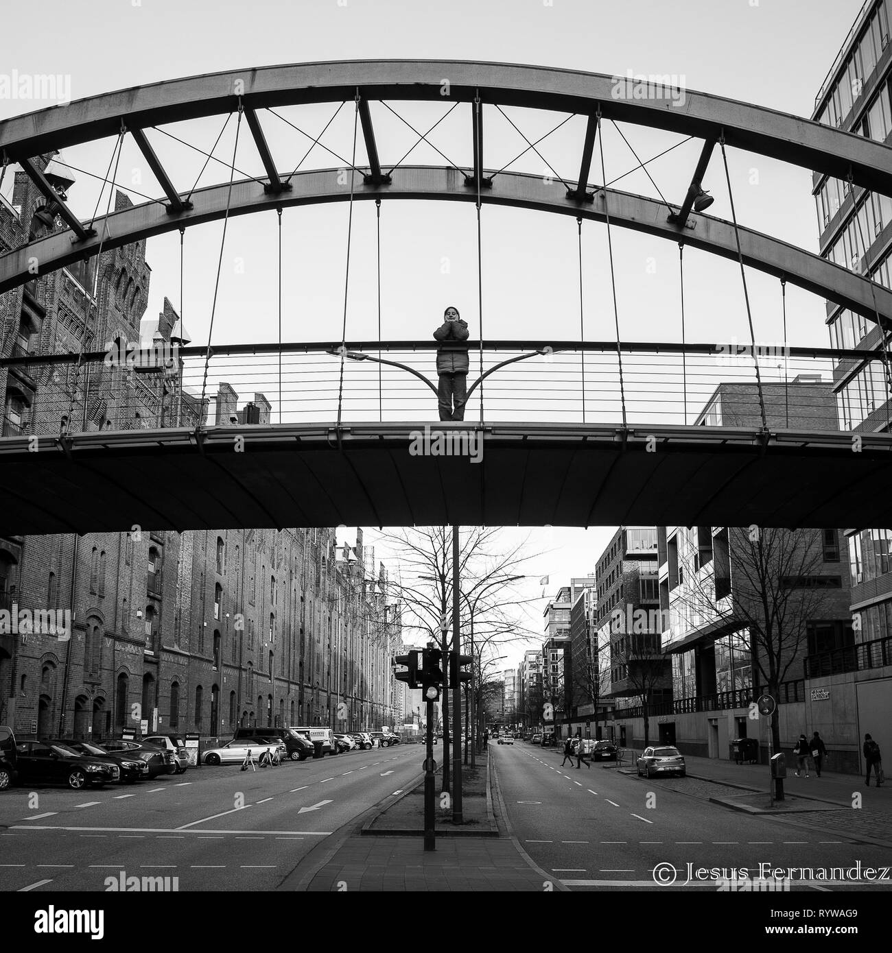 Photo en noir et blanc de garçon debout sur le pont piétonnier à Hambourg à la recherche vers le bas Banque D'Images