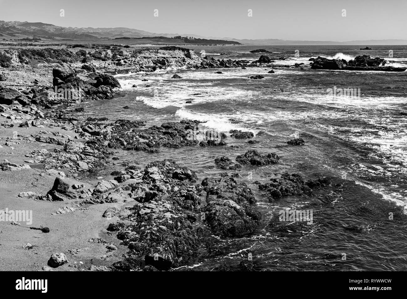 Noir et blanc, vagues se brisant sur des rochers du rivage. Banque D'Images