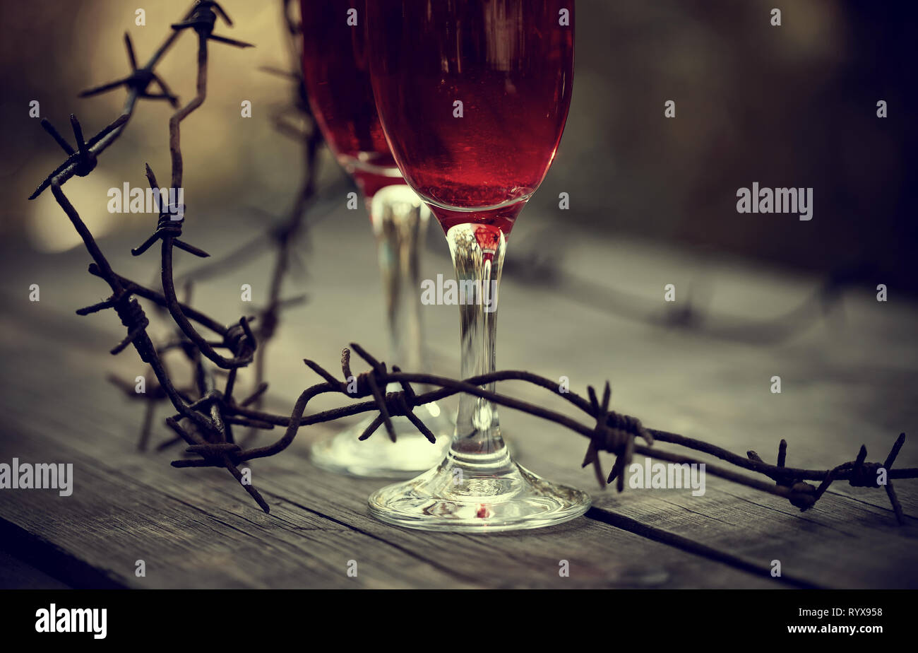 Lunettes avec boisson alcoolisée et un fil de fer barbelé rouillé sur une table en bois. La dépendance alcoolique. Banque D'Images