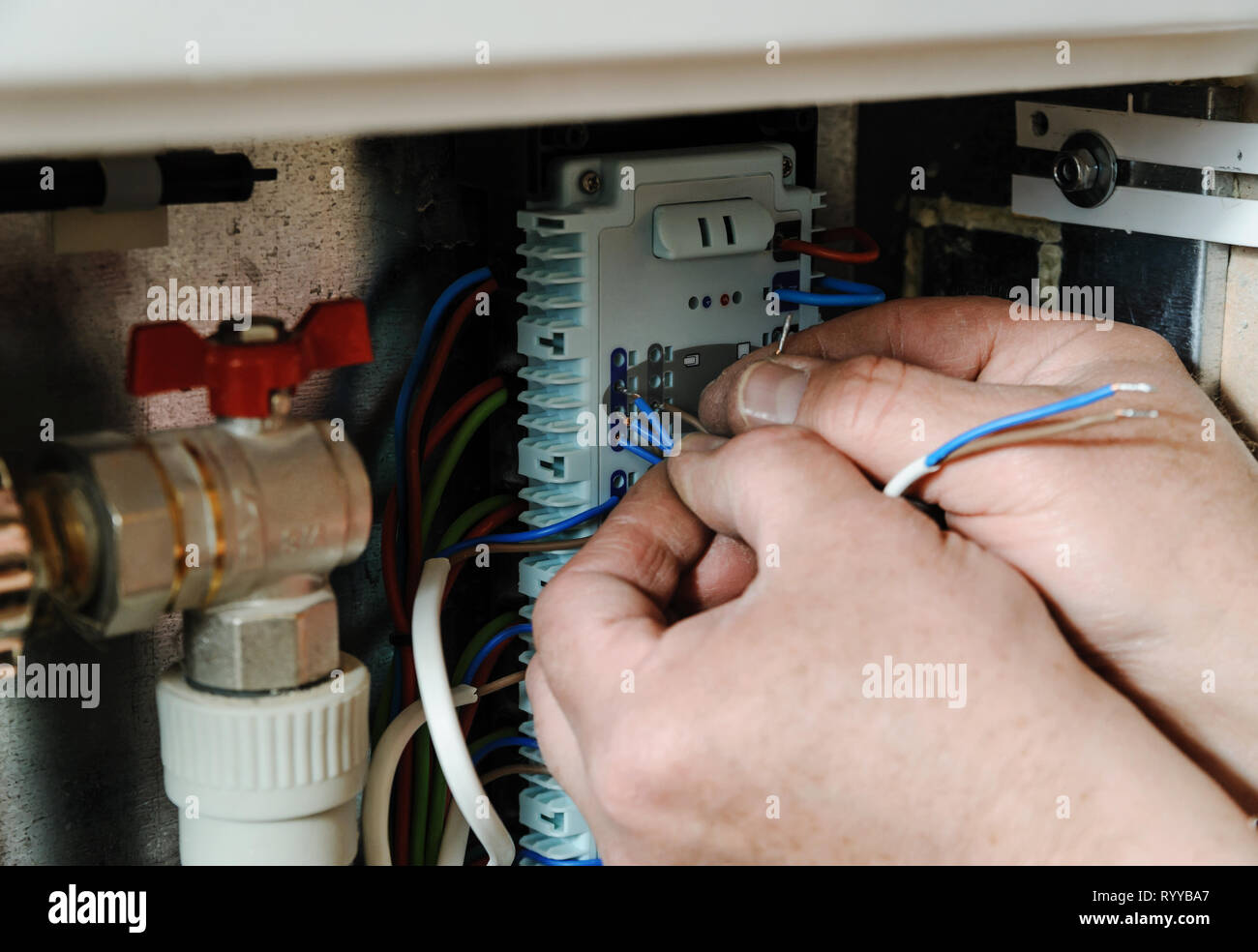 Electricien a les mains d'insérer les fils dans un commutateur pour les thermostats et les servomoteurs vannes dans un système de chauffage. Banque D'Images