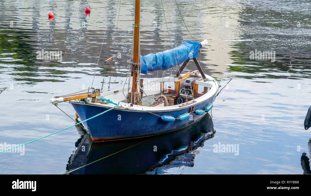 Un petit voilier qui flotte sur l'eau du fleuve ainsi que d'autres bateaux Banque D'Images