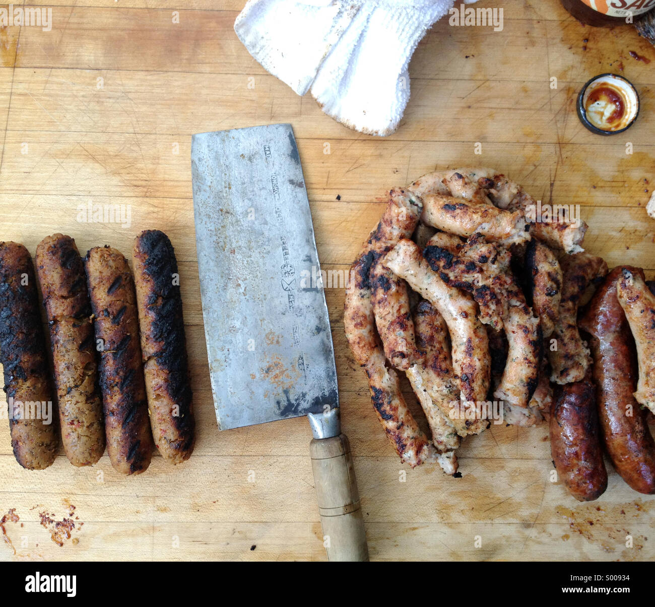 Un barbecue avec des saucisses végétariennes et vraie viande saucisse, séparés par une cleaver Banque D'Images