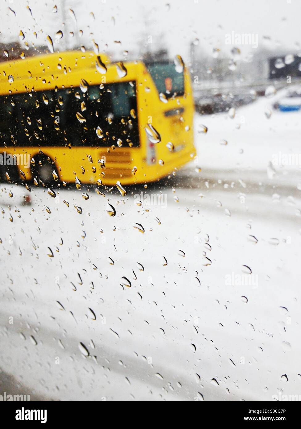 Les lecteurs de bus jaune passé avec de la pluie et de la neige humide sur la fenêtre à Uppsala, Suède. Banque D'Images