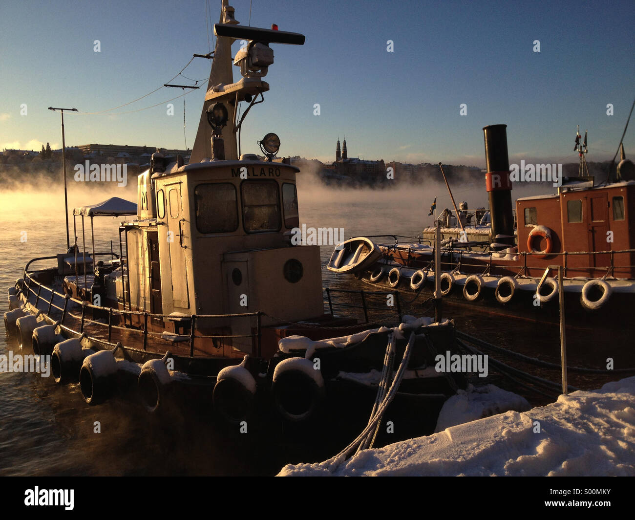 Vieux bateau amarré dans le centre de Stockholm à l'aube avec brouillard passant de l'eau d'hiver. Banque D'Images