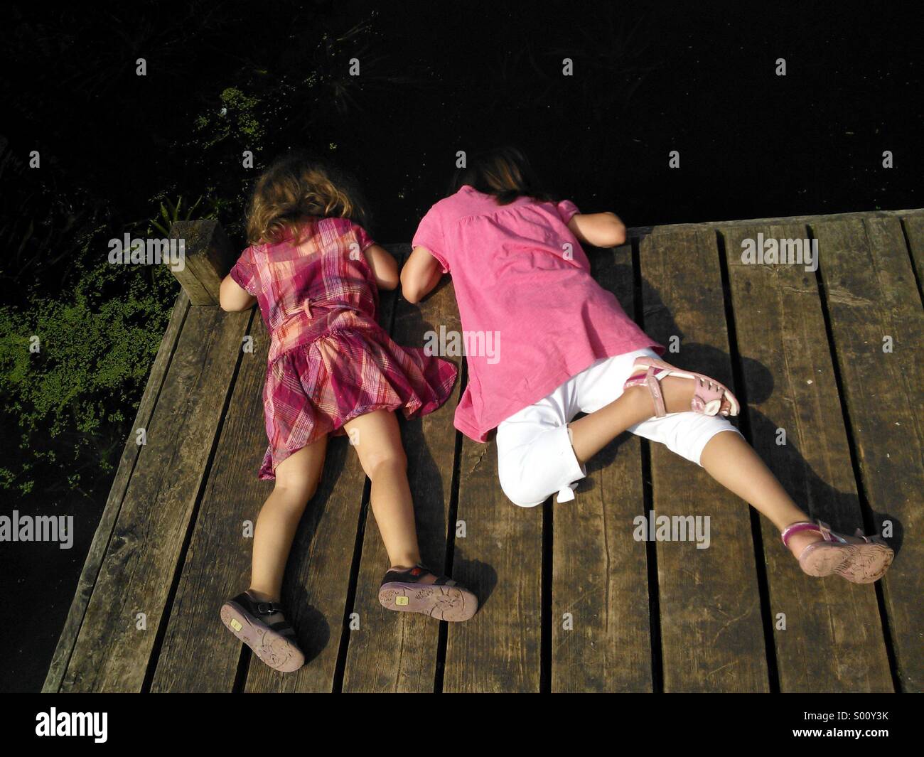 Les enfants à la recherche dans l'eau d'une jetée. Banque D'Images