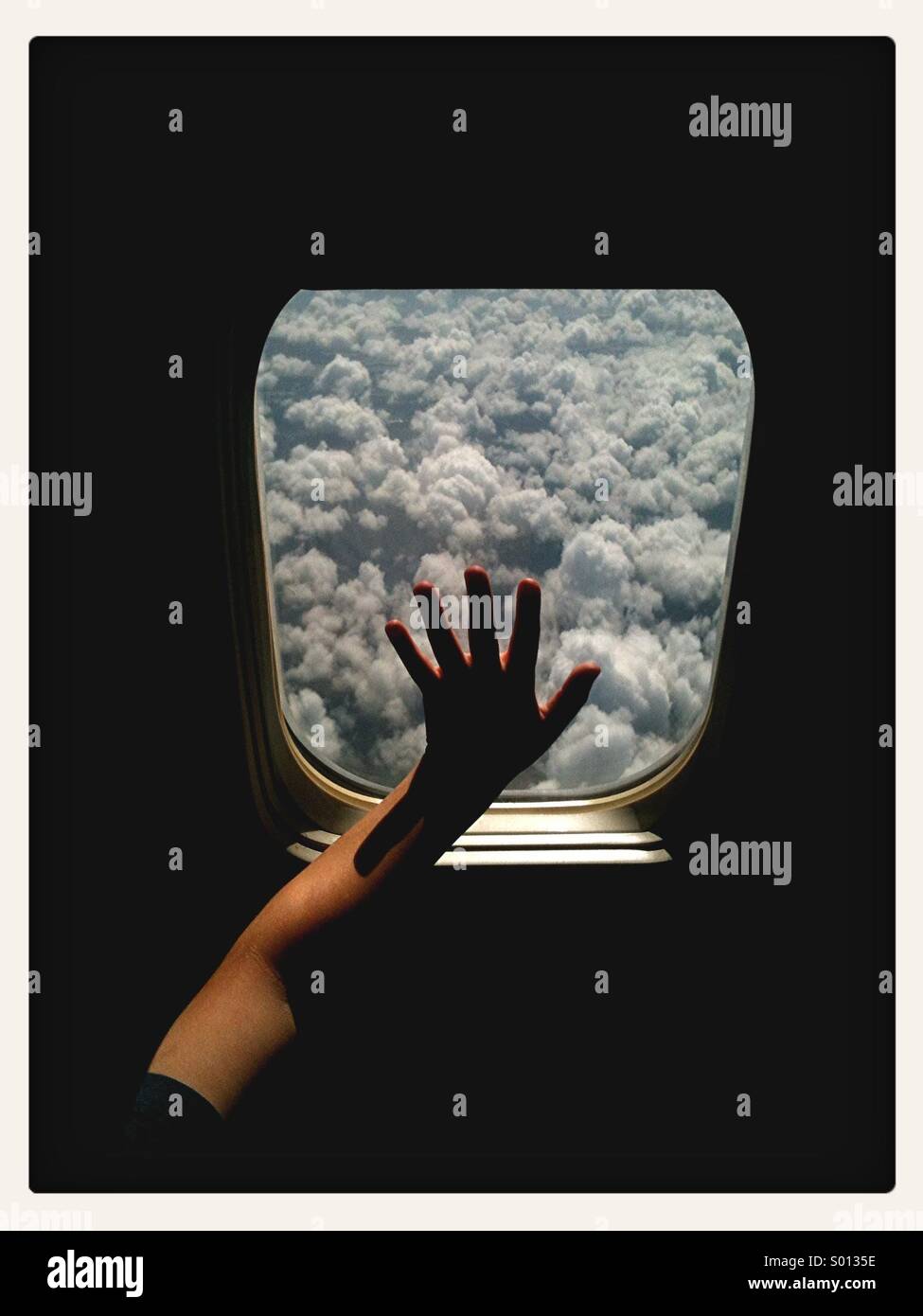 Fenêtre de toucher garçon avion en vol avec les nuages en vue. Banque D'Images