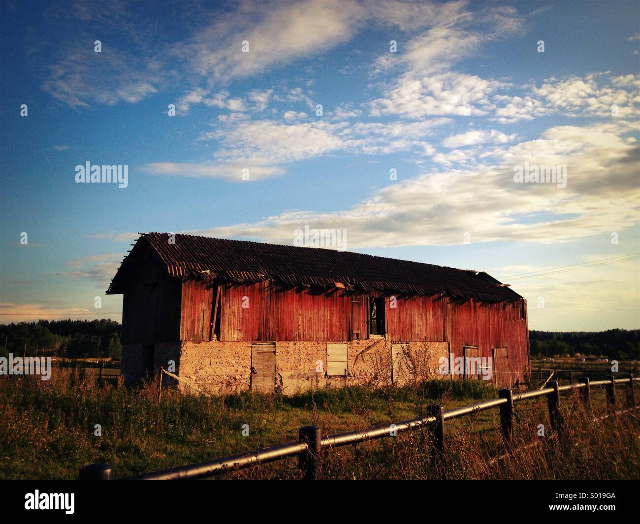 Grange Falu rouge au coucher du soleil dans la campagne suédoise. Banque D'Images