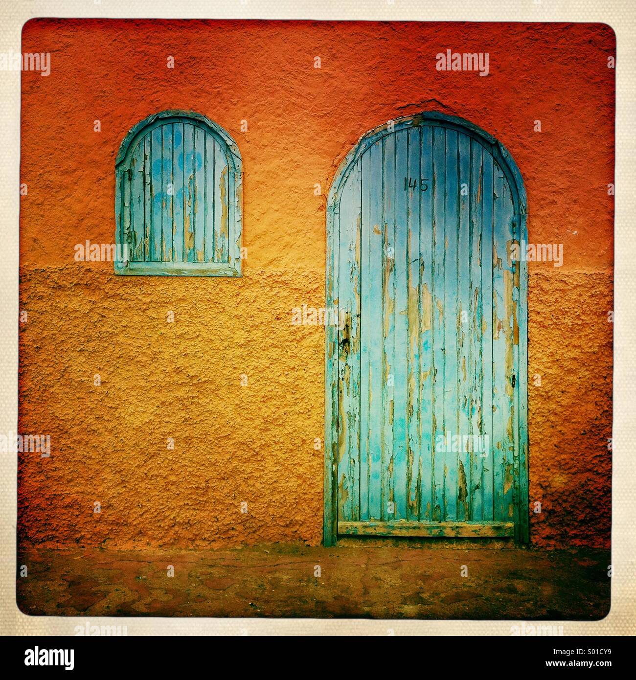 Porte bleue et fenêtre contre orange wall au Maroc. Banque D'Images