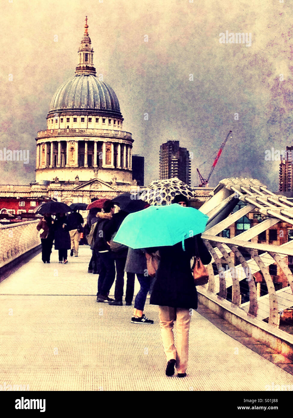 Femme avec un parapluie turquoise traverse le Millenium Bridge à Londres avec la Cathédrale St Paul à l'arrière-plan. Banque D'Images