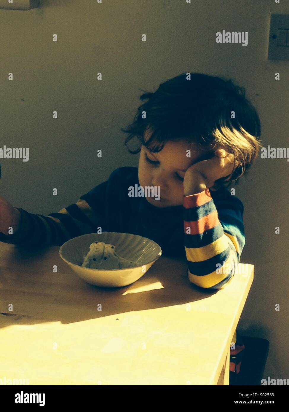 Boy eating ice cream dans Sunbeam avec stripe top. Banque D'Images