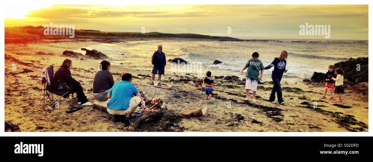 Une famille bénéficiant d'un feu et de l'amusement sur une plage écossaise à distance Banque D'Images
