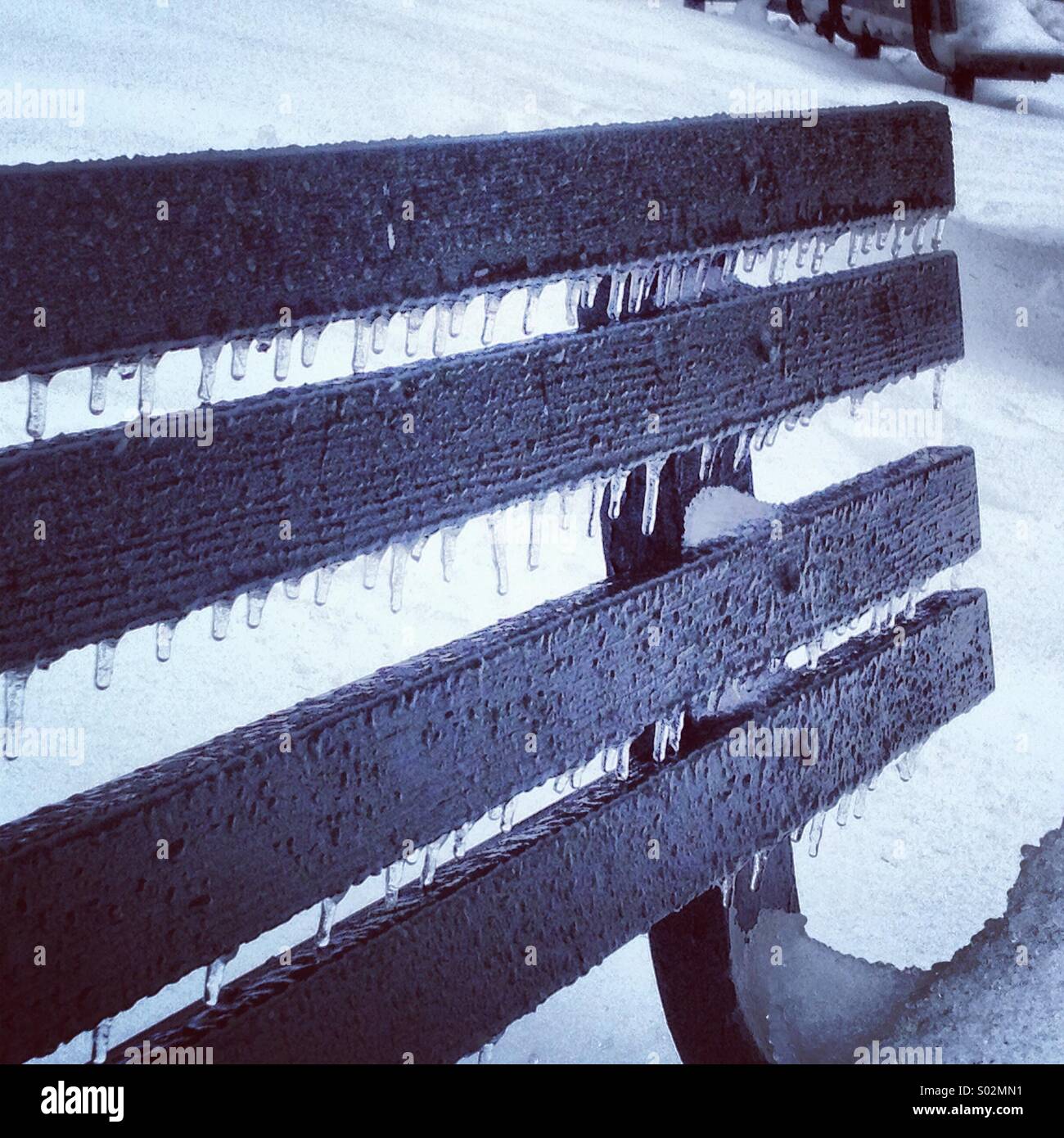 Les glaçons sur banc de parc en pluie verglaçante et de neige Banque D'Images