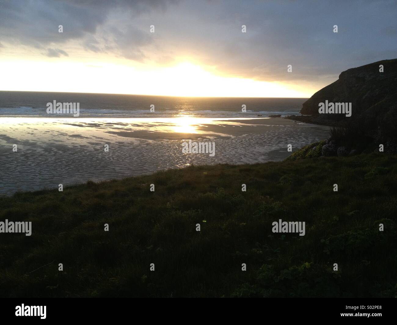 Mawgan Porth Cornwall. Coucher du soleil sur une mer calme. Banque D'Images