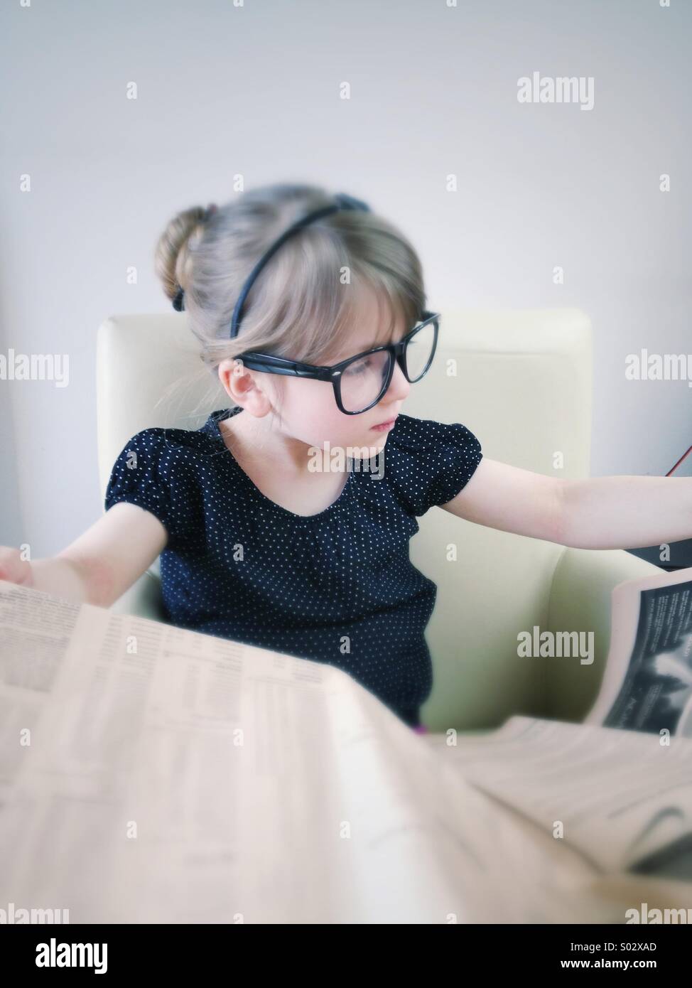 Little girl reading newspaper Banque D'Images