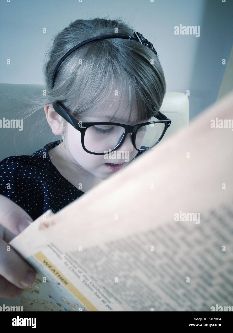 Little girl reading newspaper Banque D'Images