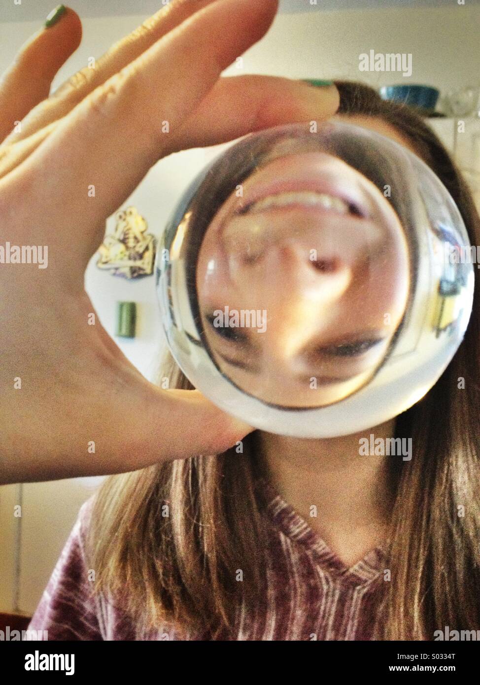 Girl holding up crystal ball montrant l'envers funny face Banque D'Images