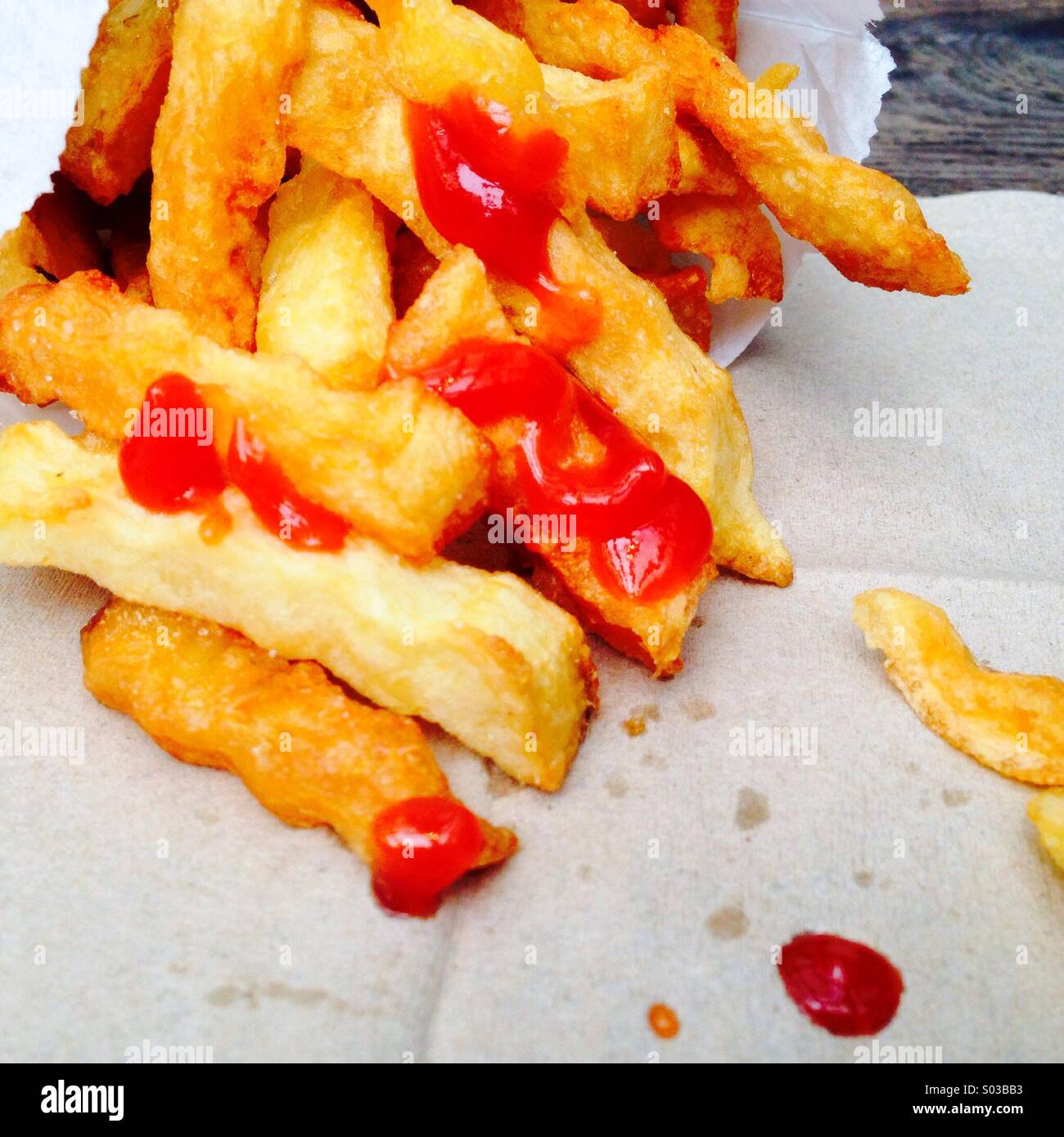 Frites avec du ketchup et Chunky les taches de ketchup sur une serviette Banque D'Images