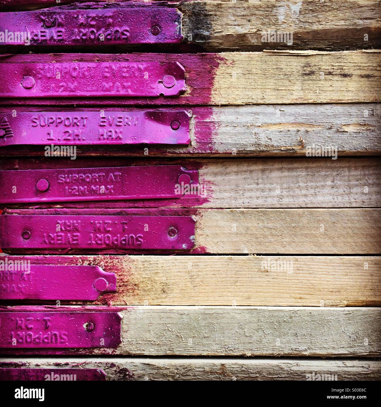Planches en bois teint avec extrémités violettes empilées dans un tas. Banque D'Images