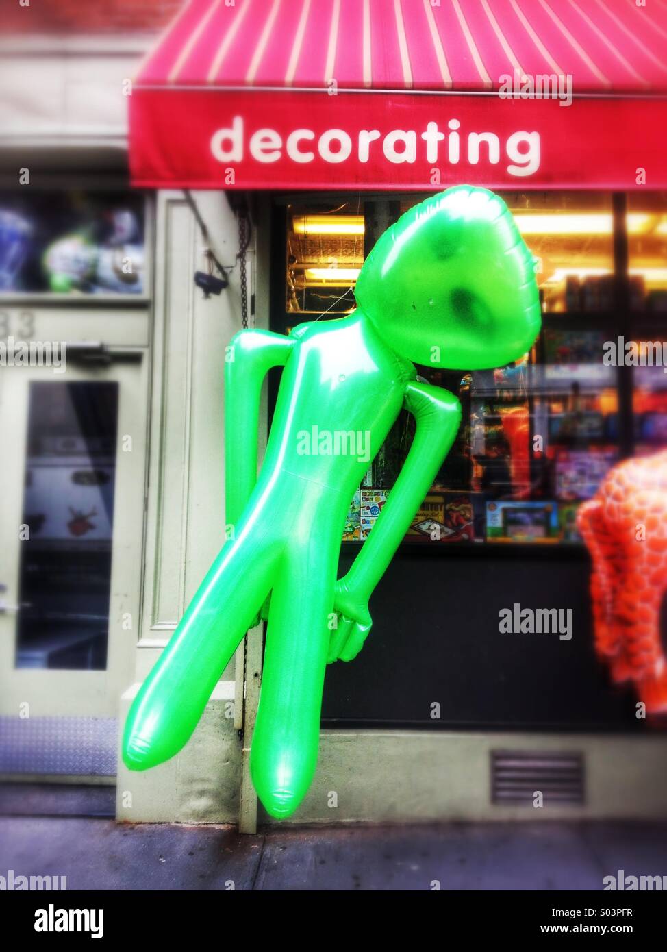 Grand jouet alien gonflable accroché en face de vitrine de magasin Banque D'Images