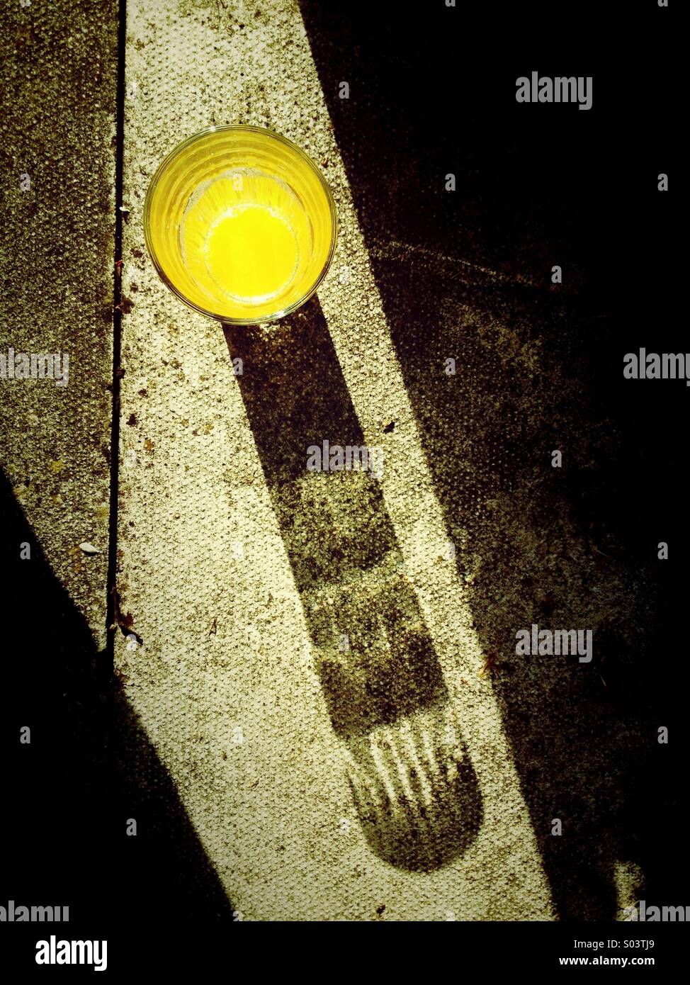 Si le verre de jus d'orange casting long shadow Banque D'Images