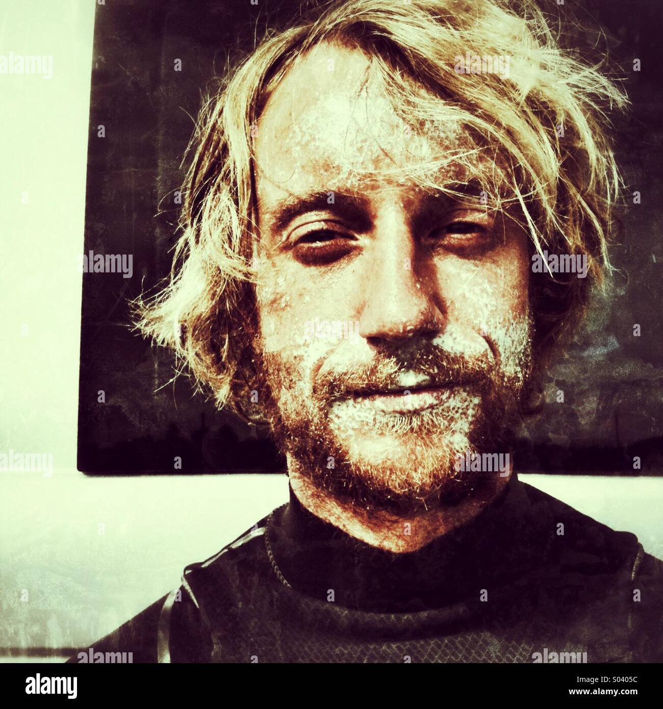 Surfer en combinaison avec des cheveux longs et de sable sur son visage Banque D'Images