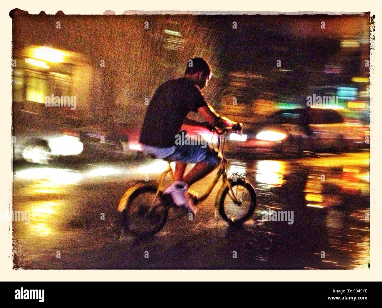 Boy riding bicycle la nuit humide sur New York City Street Banque D'Images