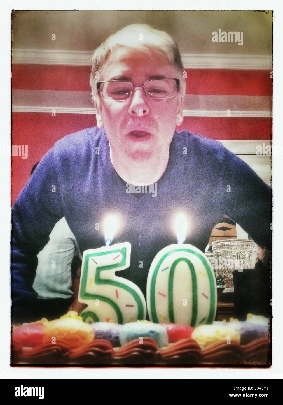 Homme de 50 ans à une fête d'anniversaire sur le point de souffler les bougies sur le gâteau Banque D'Images